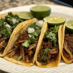 Juicy birria tacos dipped in consommé with lime and cilantro